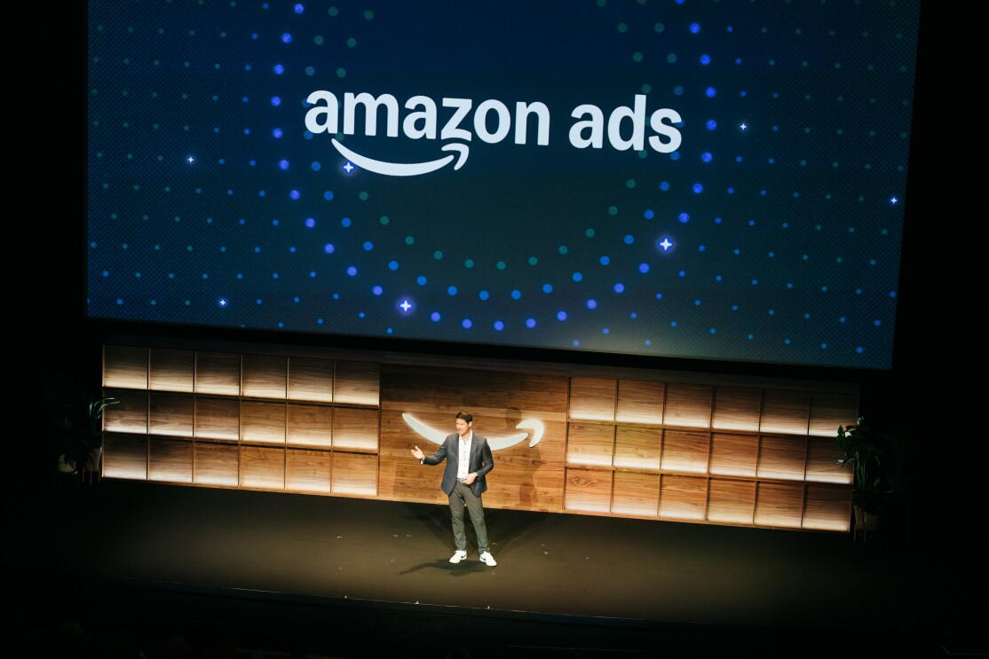 A presenter on stage in front of an Amazon Ads logo
