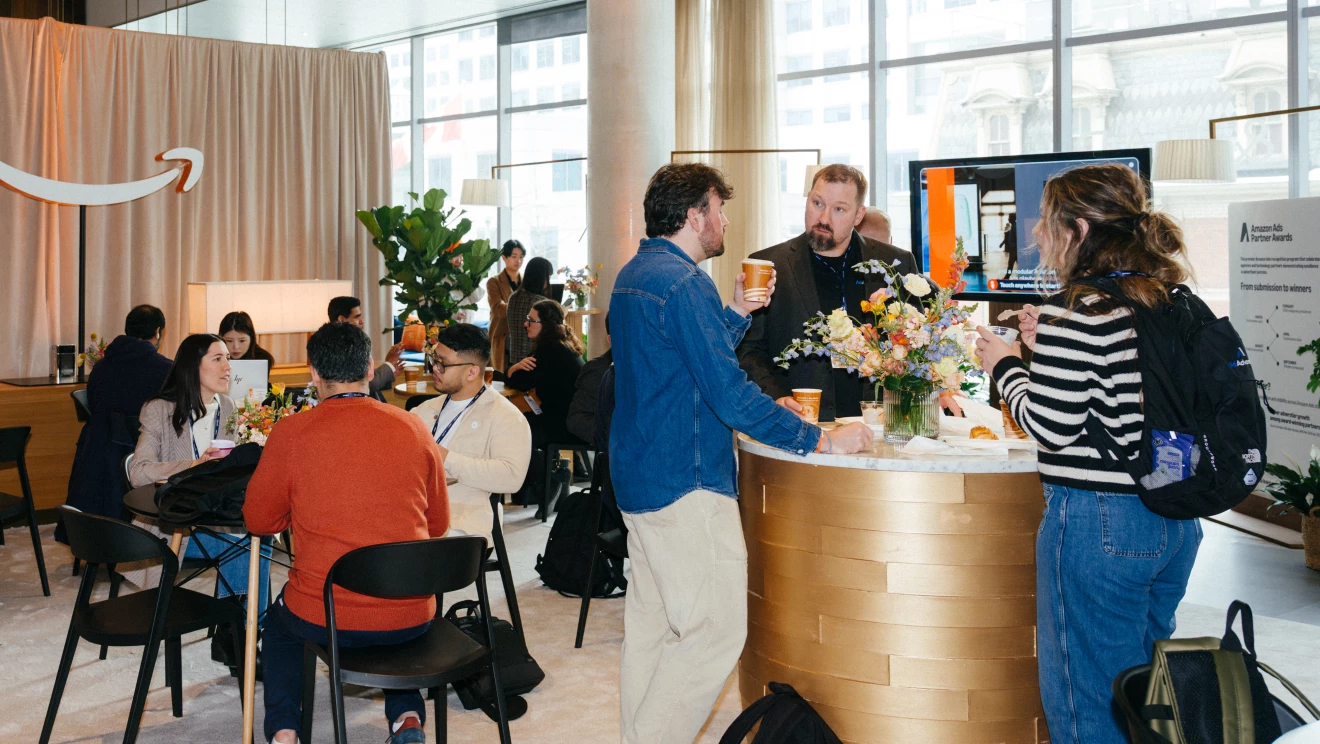 A group of people socializing in a modern open space with an Amazon logo