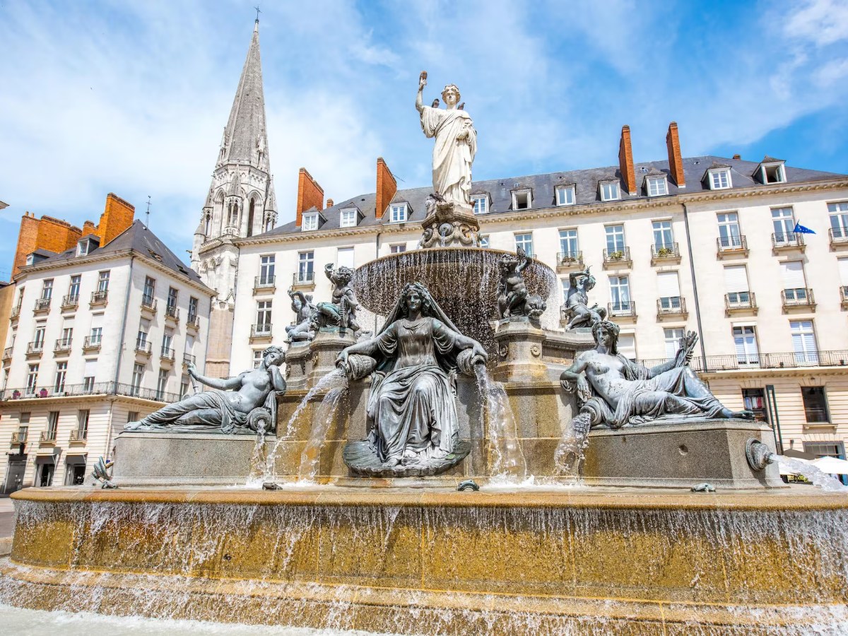 Fountain with statues and flowing water in front of a large building