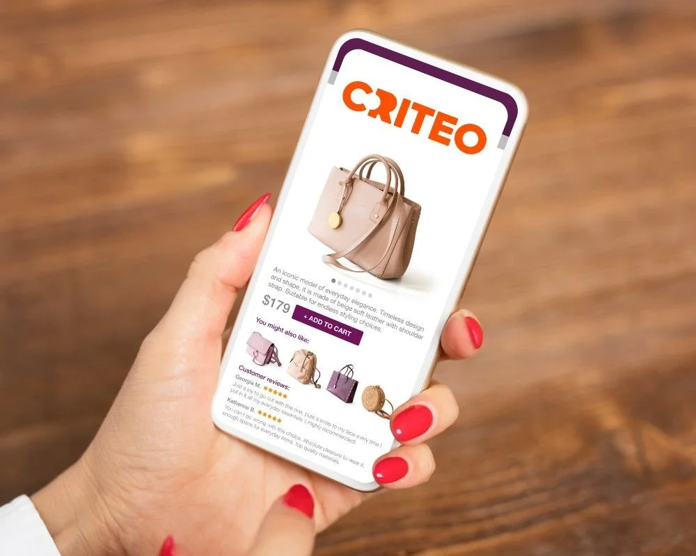 A woman is holding a phone that says 'Criteo' and shows a handbag for sale.